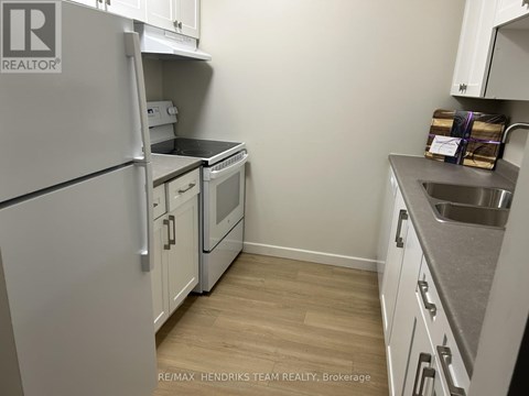 A kitchen with a refrigerator, oven, and sink.
