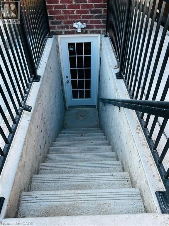 A set of stairs leading to a door at the bottom of a stairwell.