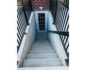 A set of stairs leading to a door at the bottom of a stairwell.