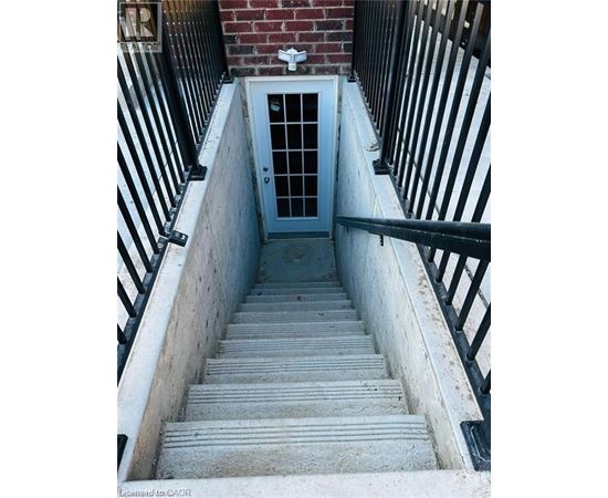 A set of stairs leading to a door at the bottom of a stairwell.