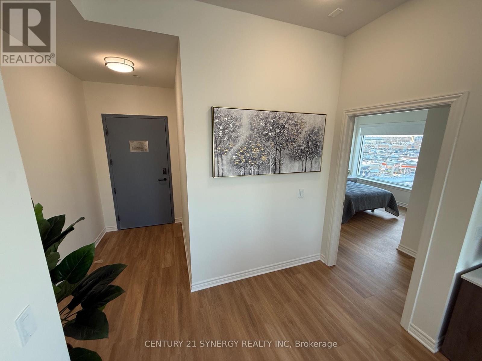A room with a painting of trees on the wall and a bed in the other room.