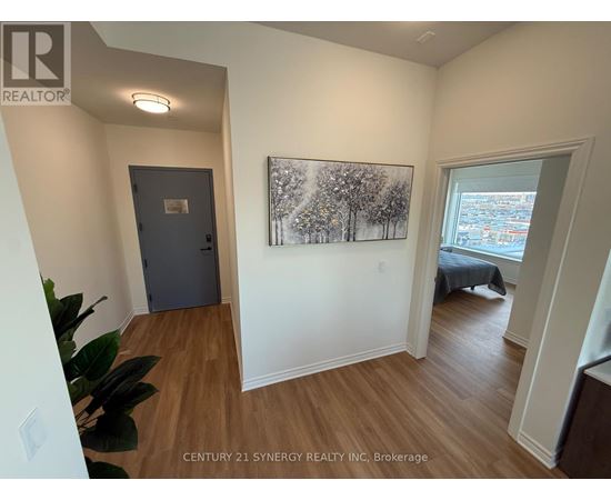 A room with a painting of trees on the wall and a bed in the other room.