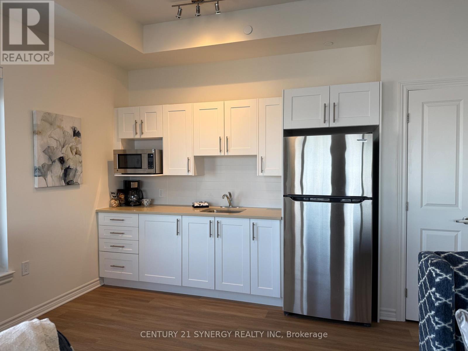 A kitchen with white cabinets and a stainless steel refrigerator.
