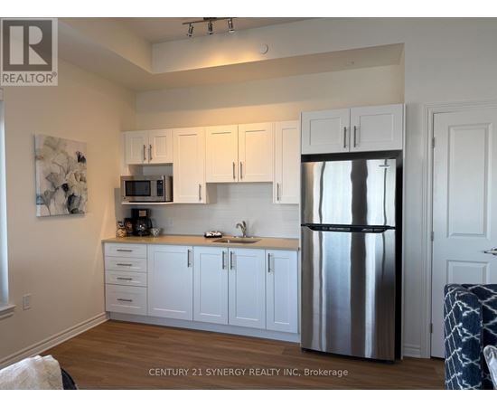 A kitchen with white cabinets and a stainless steel refrigerator.