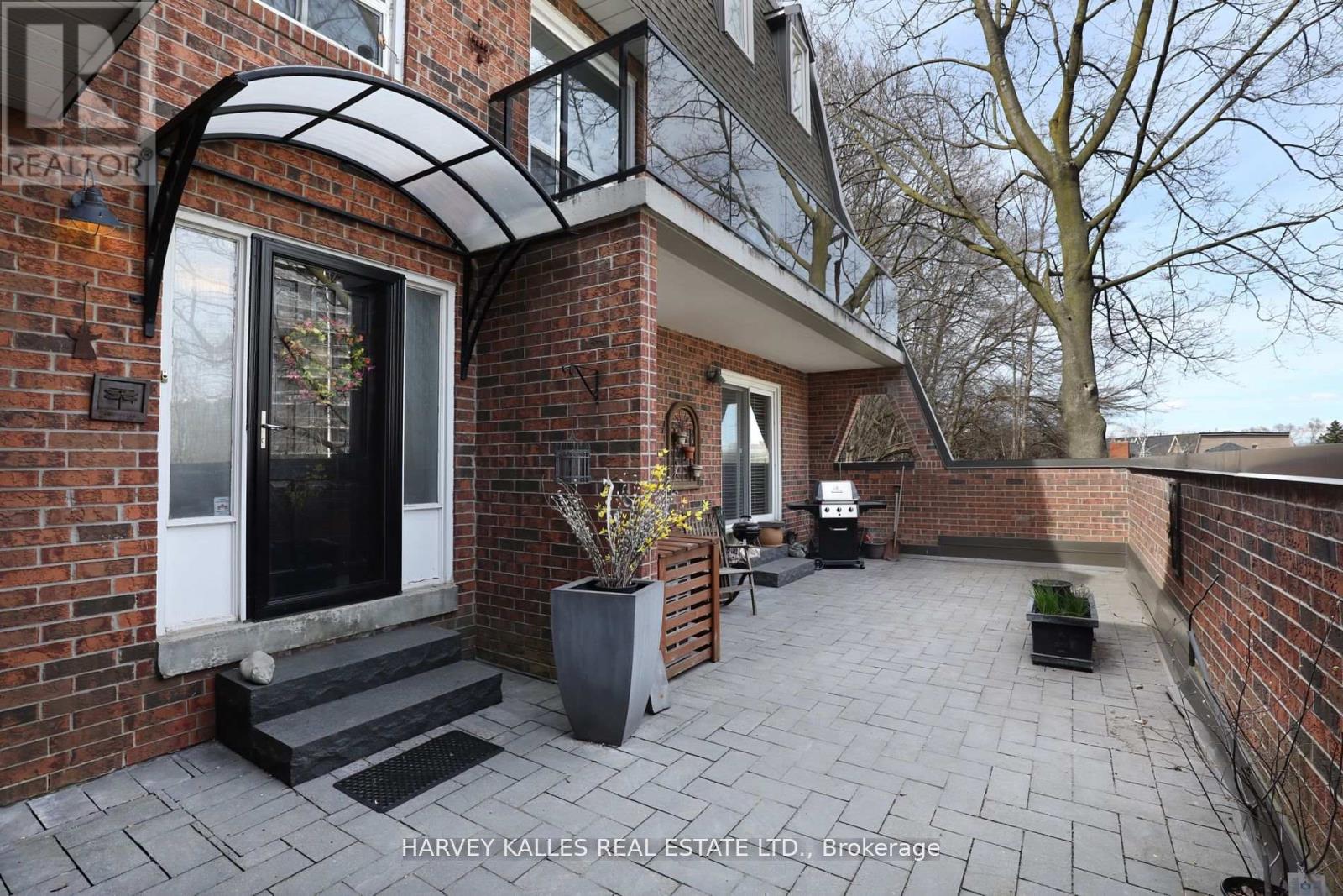 A brick house with a patio and a sign that says Harvey Kalles Real Estate Ltd.