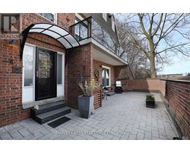 A brick house with a patio and a sign that says Harvey Kalles Real Estate Ltd.
