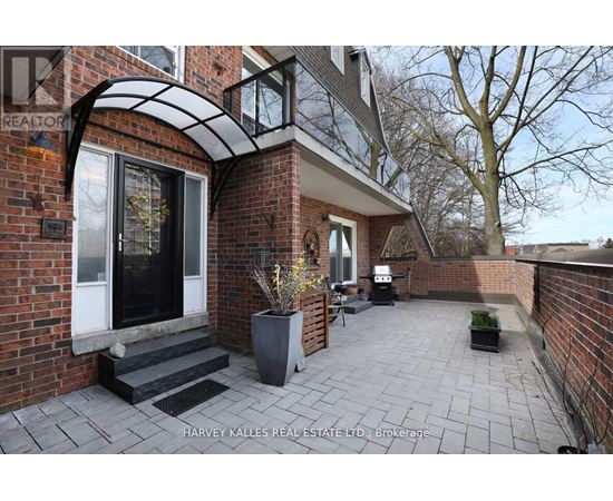 A brick house with a patio and a sign that says Harvey Kalles Real Estate Ltd.