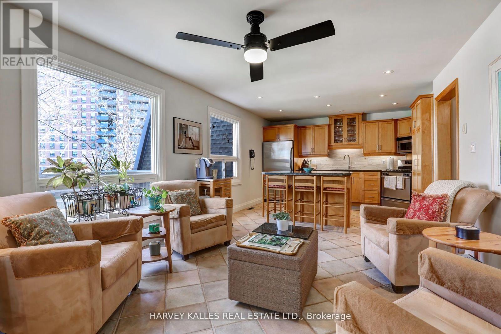 A living room with a fan and a kitchen in the background.