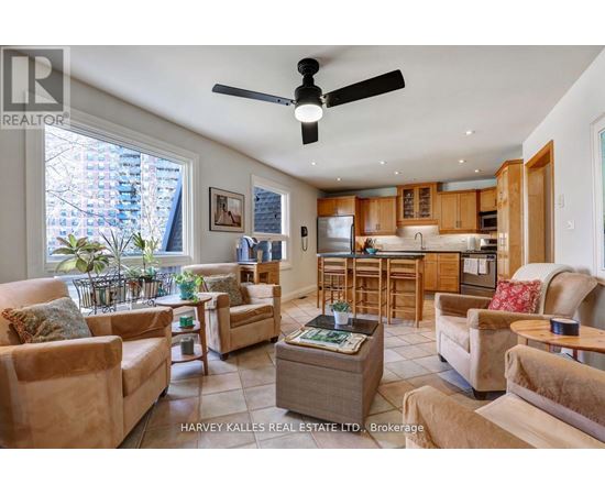 A living room with a fan and a kitchen in the background.
