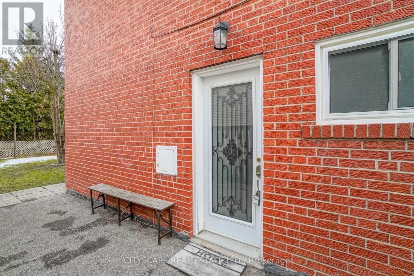 A red brick building with a white door and a bench in front.