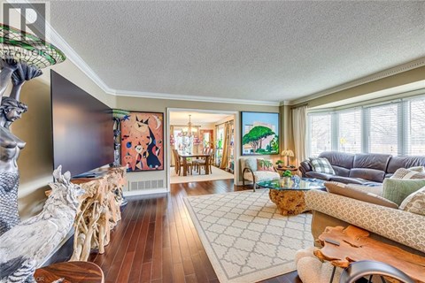 A living room with a wooden floor and a large painting on the wall.