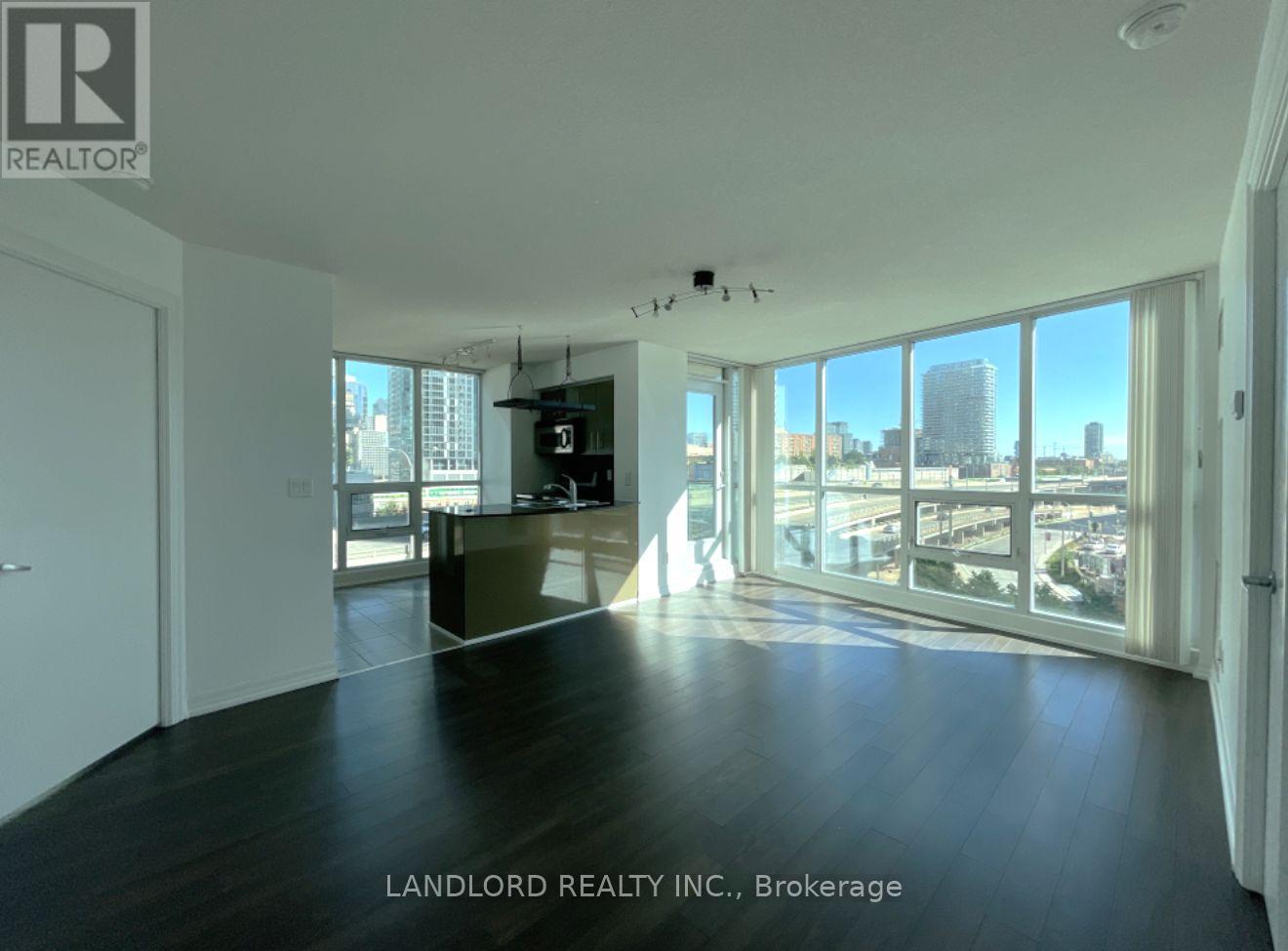 A spacious room with a view of the cityscape through large windows.