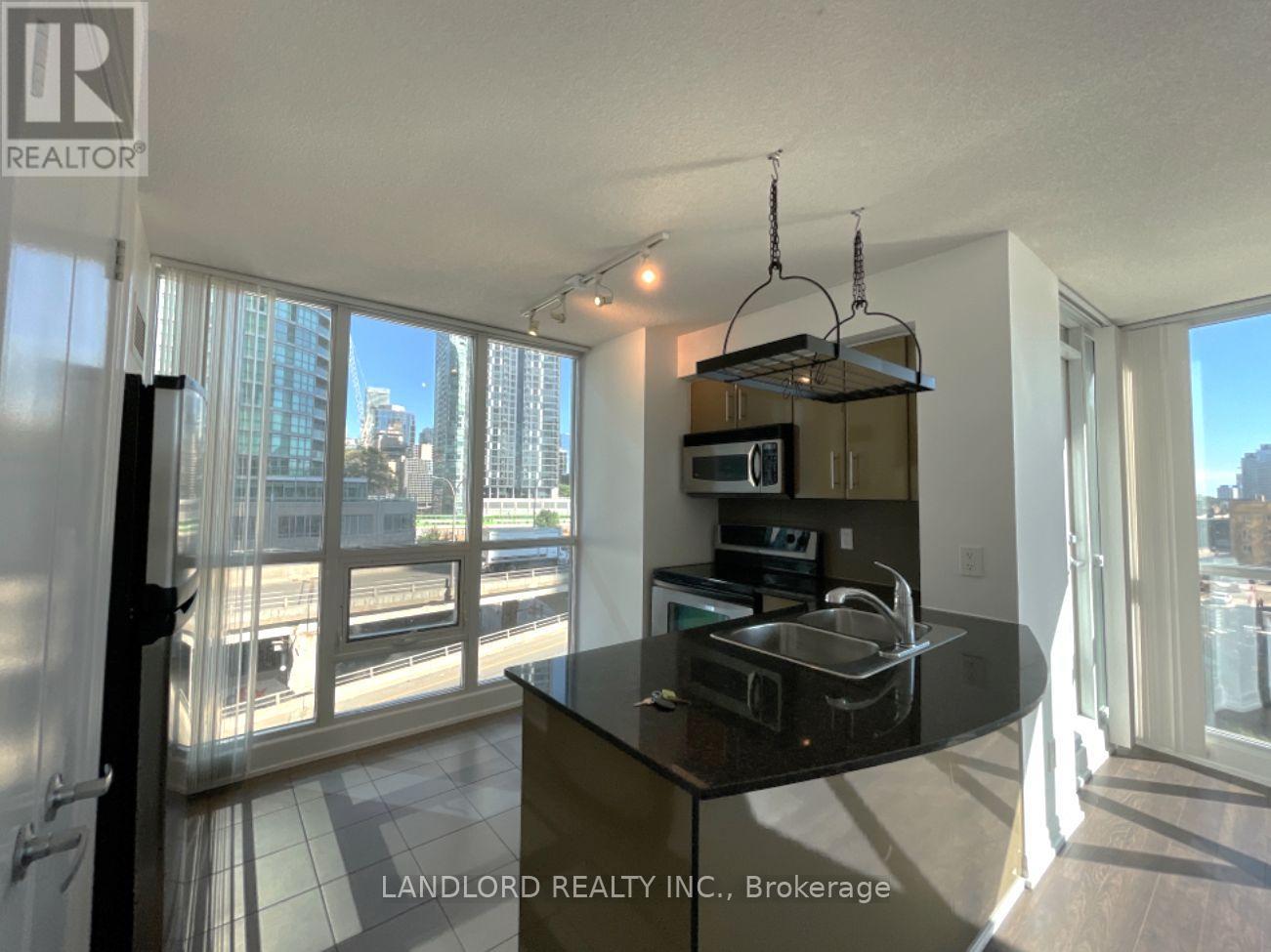 A kitchen with a black countertop and a microwave on top.