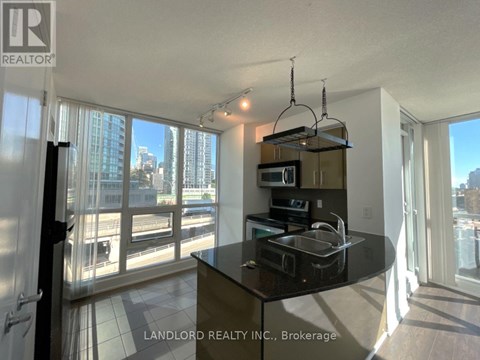 A kitchen with a black countertop and a microwave on top.