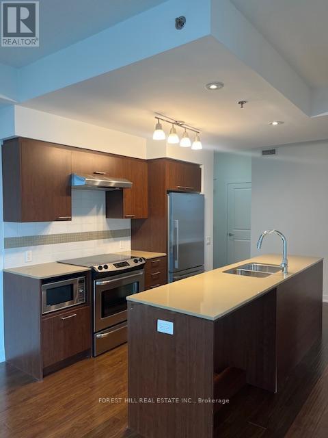A kitchen with wooden cabinets and a stainless steel refrigerator.