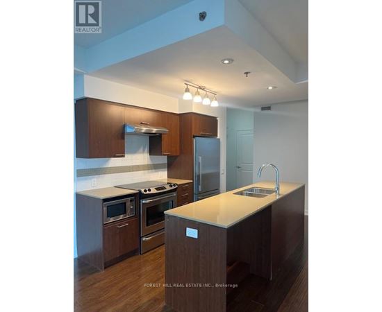 A kitchen with wooden cabinets and a stainless steel refrigerator.