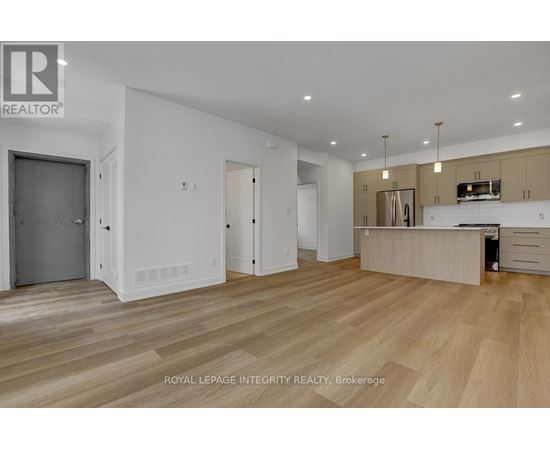 A spacious room with wooden flooring and a kitchen area with a stove top oven.