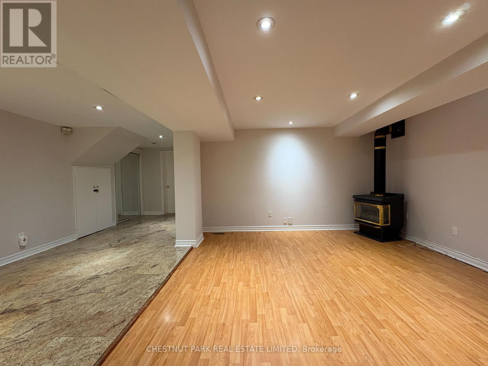 A spacious room with wood flooring and a wood-burning stove.