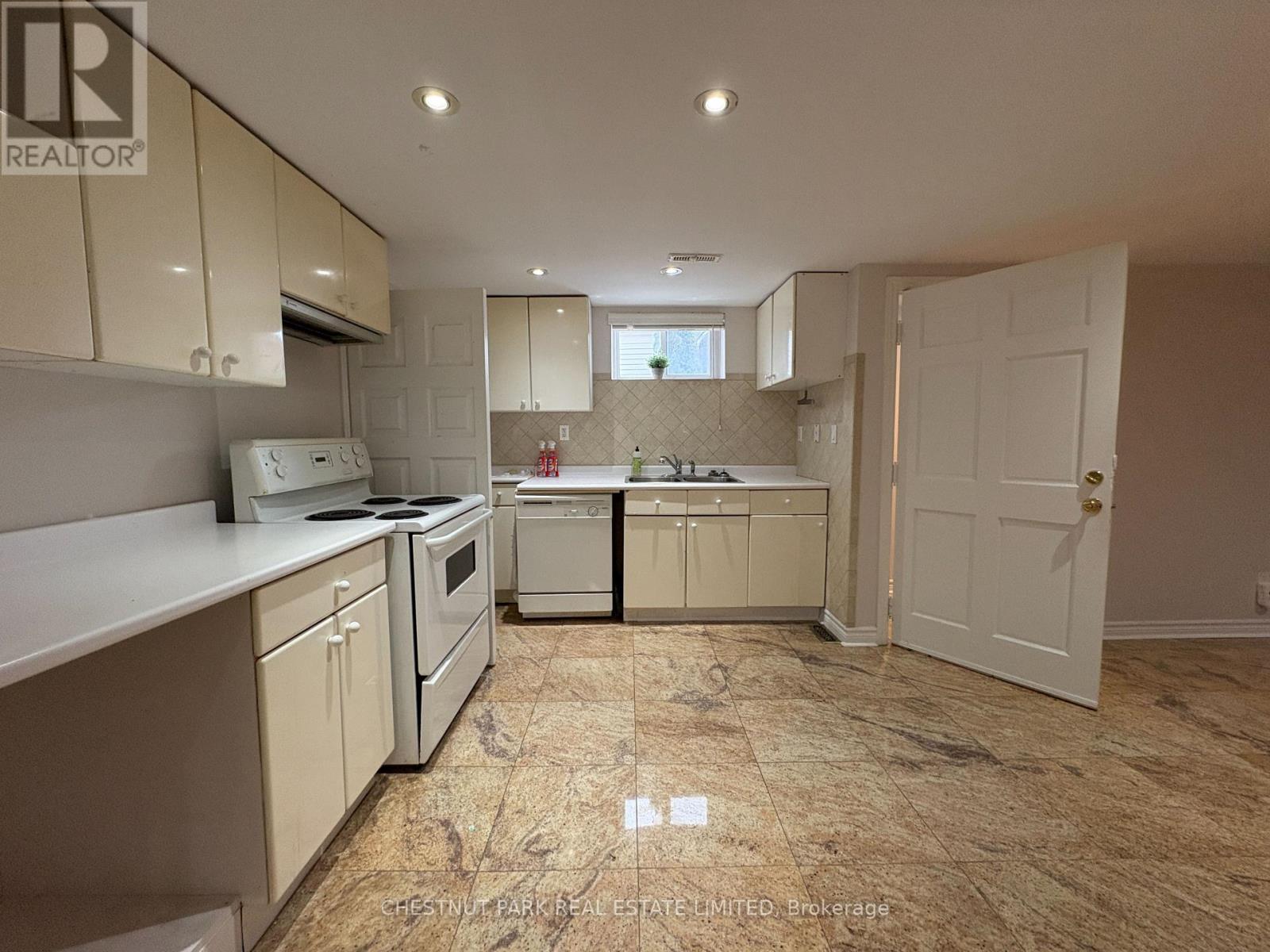A kitchen with beige cabinets and a tiled floor.