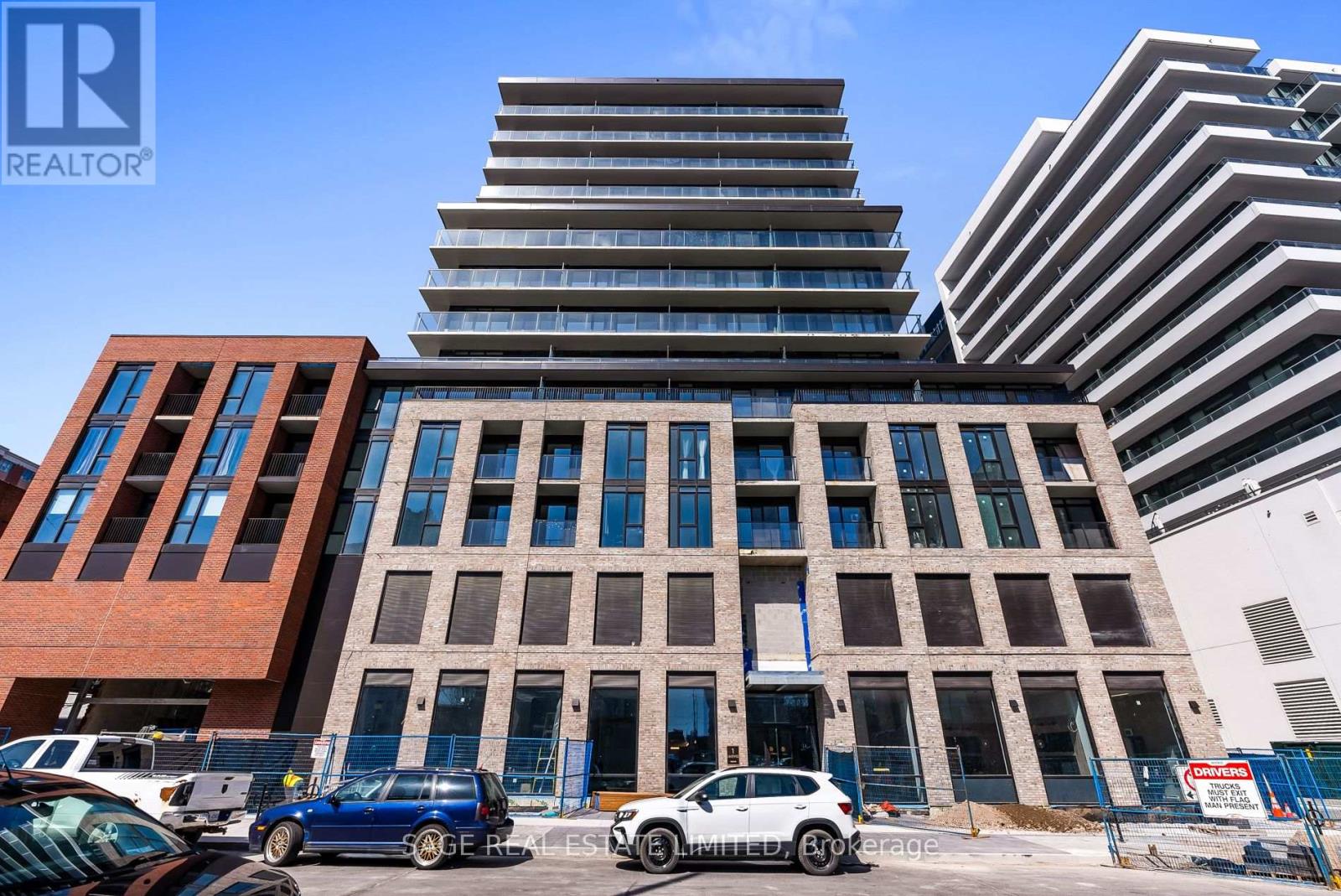 A modern multi-story building with a parking lot in front.