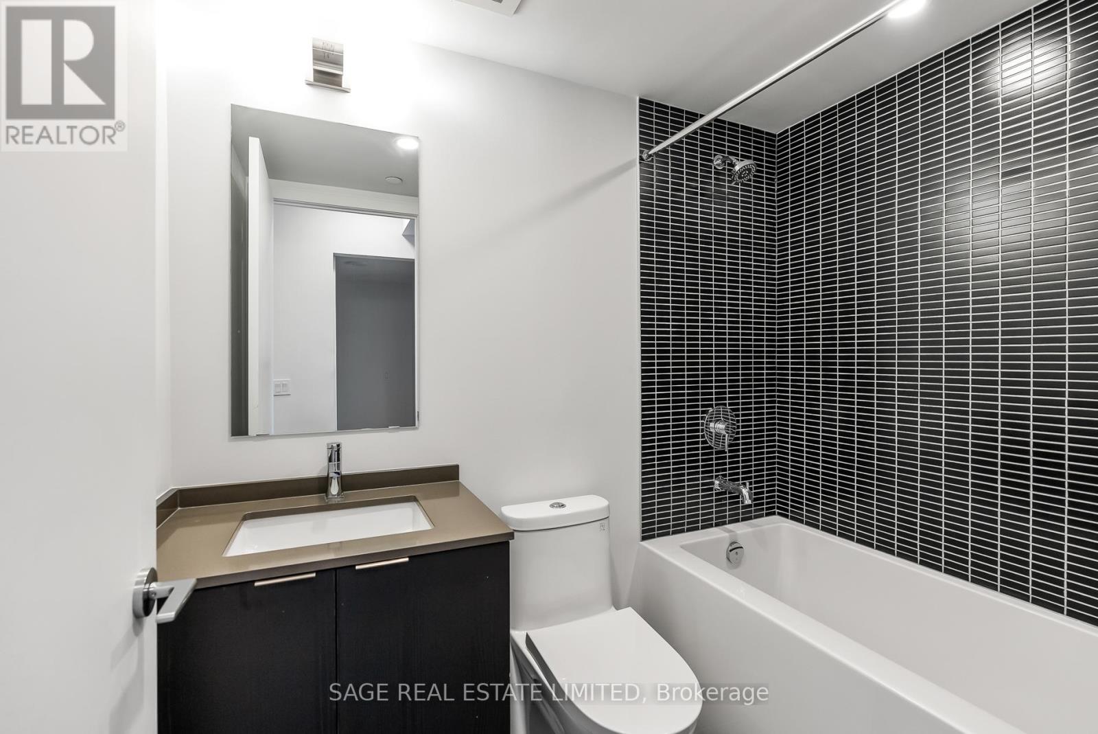 A bathroom with a black and white tiled wall.