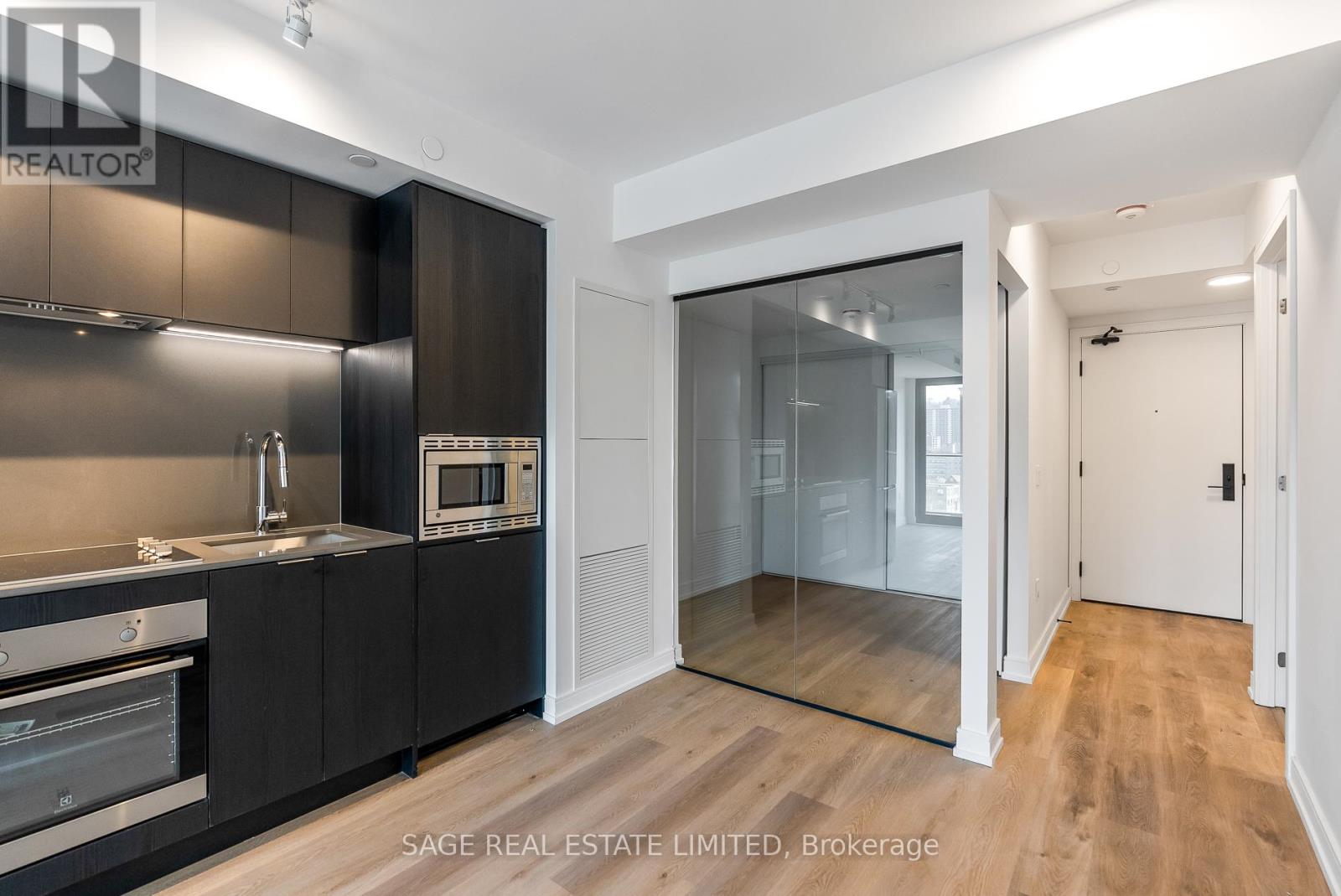A modern kitchen with dark brown cabinets and stainless steel appliances.