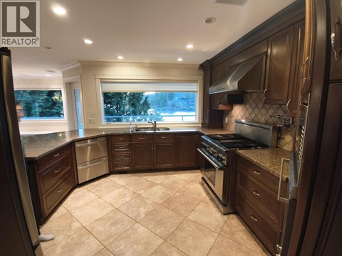 A well-lit kitchen with dark wood cabinets and a tiled floor.