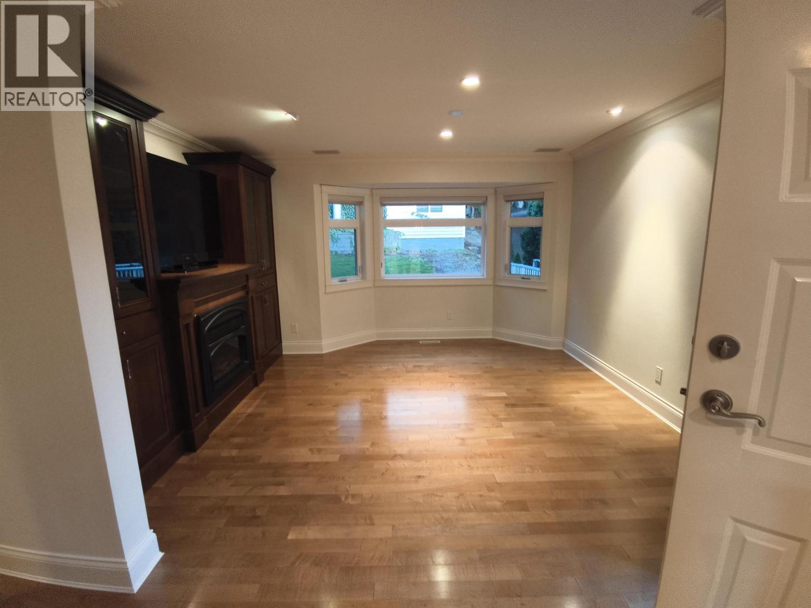 A room with wooden floors and a door on the right side.