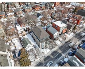A winter scene of a residential area with houses and cars.