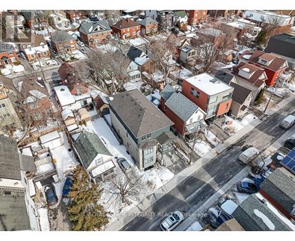 A winter scene of a residential area with houses and cars.