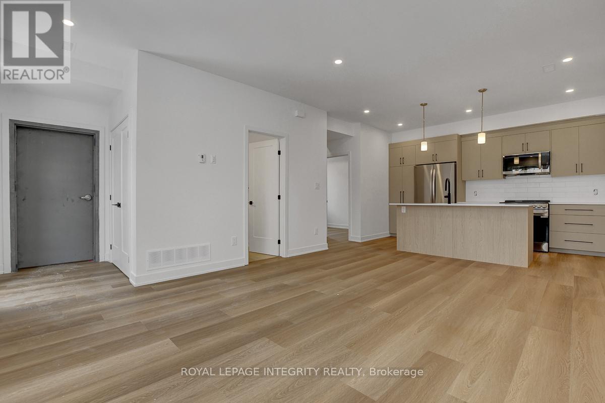 A spacious room with wooden flooring and a kitchen area with a stove top oven.