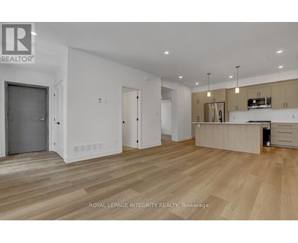 A spacious room with wooden flooring and a kitchen area with a stove top oven.