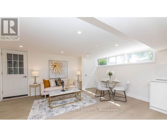 A well-lit, spacious living room with a white sofa, a coffee table, and a dining table set up.