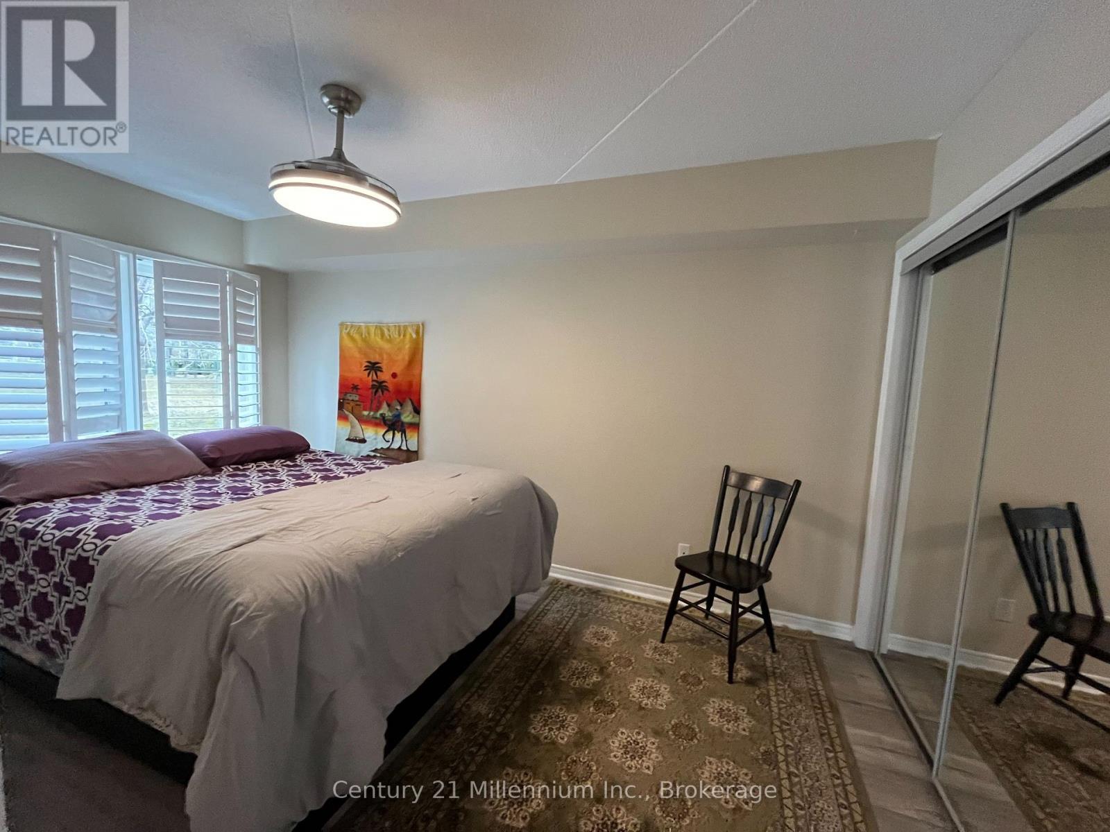 A bedroom with a bed, chair, and painting.