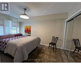 A bedroom with a bed, chair, and painting.