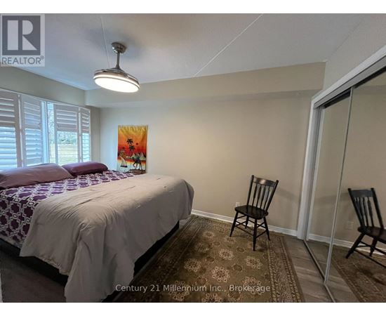 A bedroom with a bed, chair, and painting.