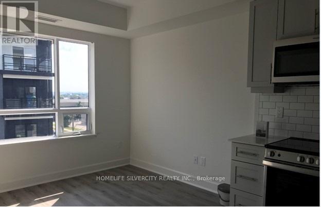 A kitchen with white cabinets and a window overlooking a balcony.