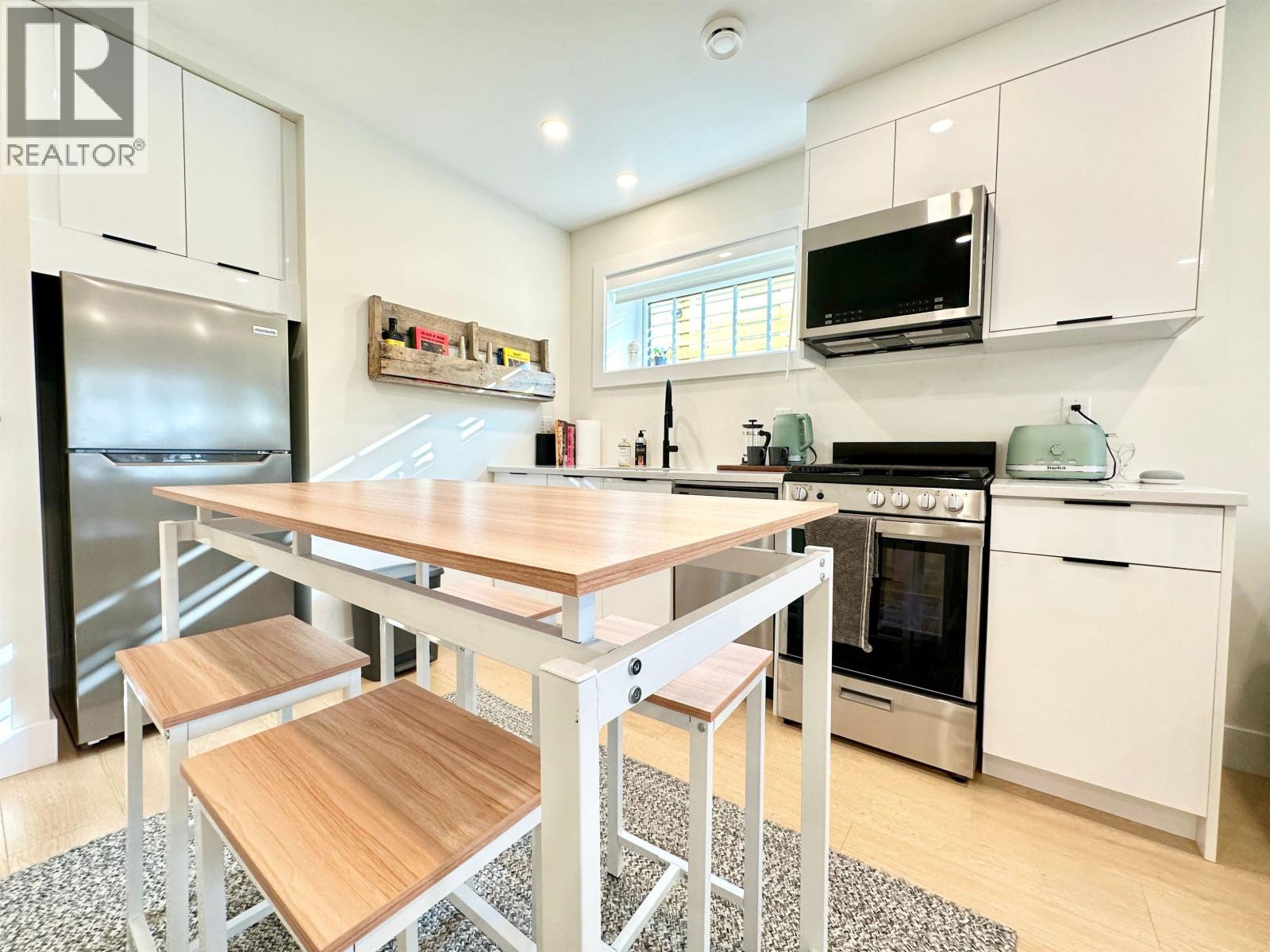 A modern kitchen with a wooden table and stools.