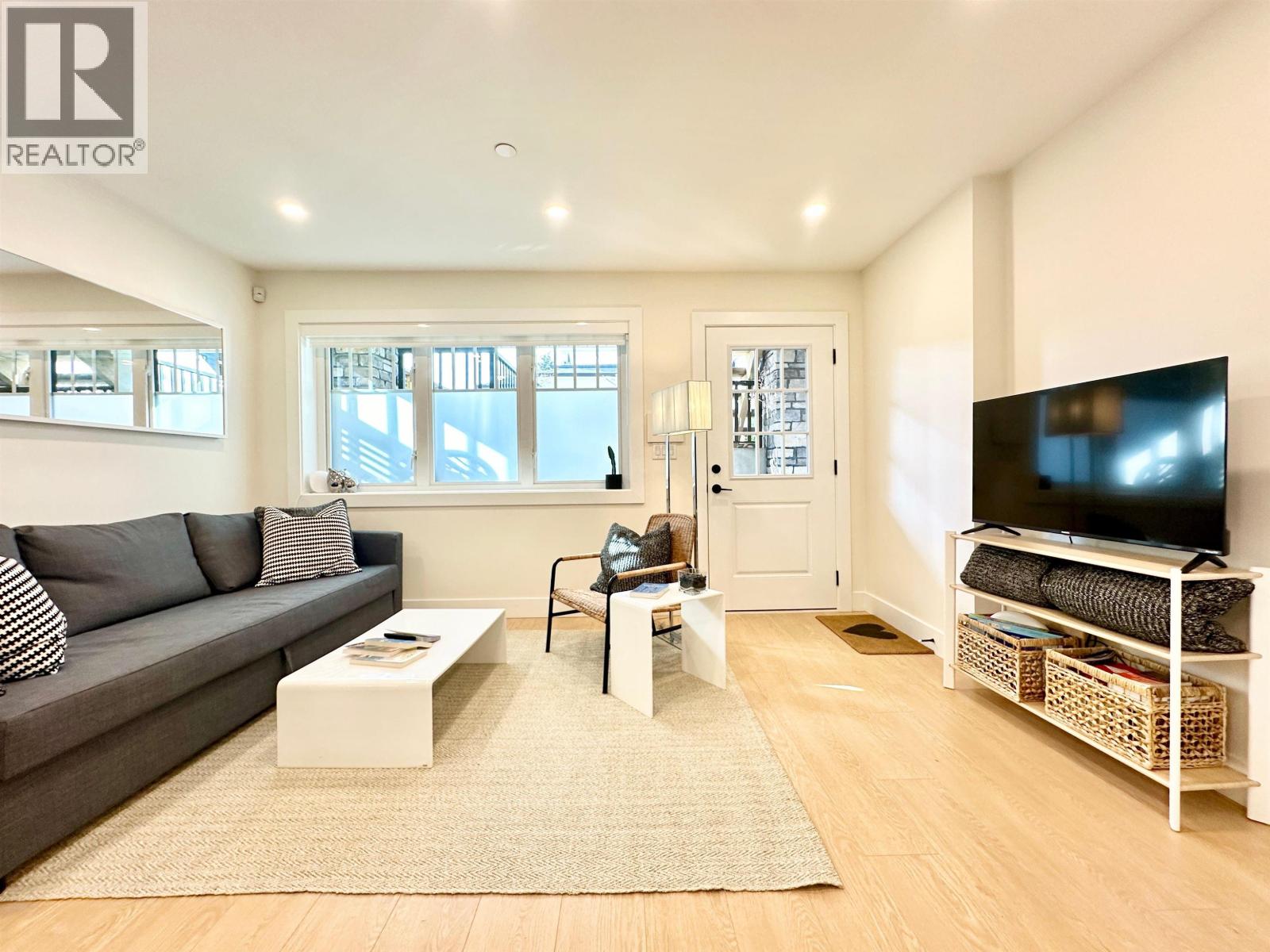 A living room with a grey couch, a white coffee table, and a flat screen TV.