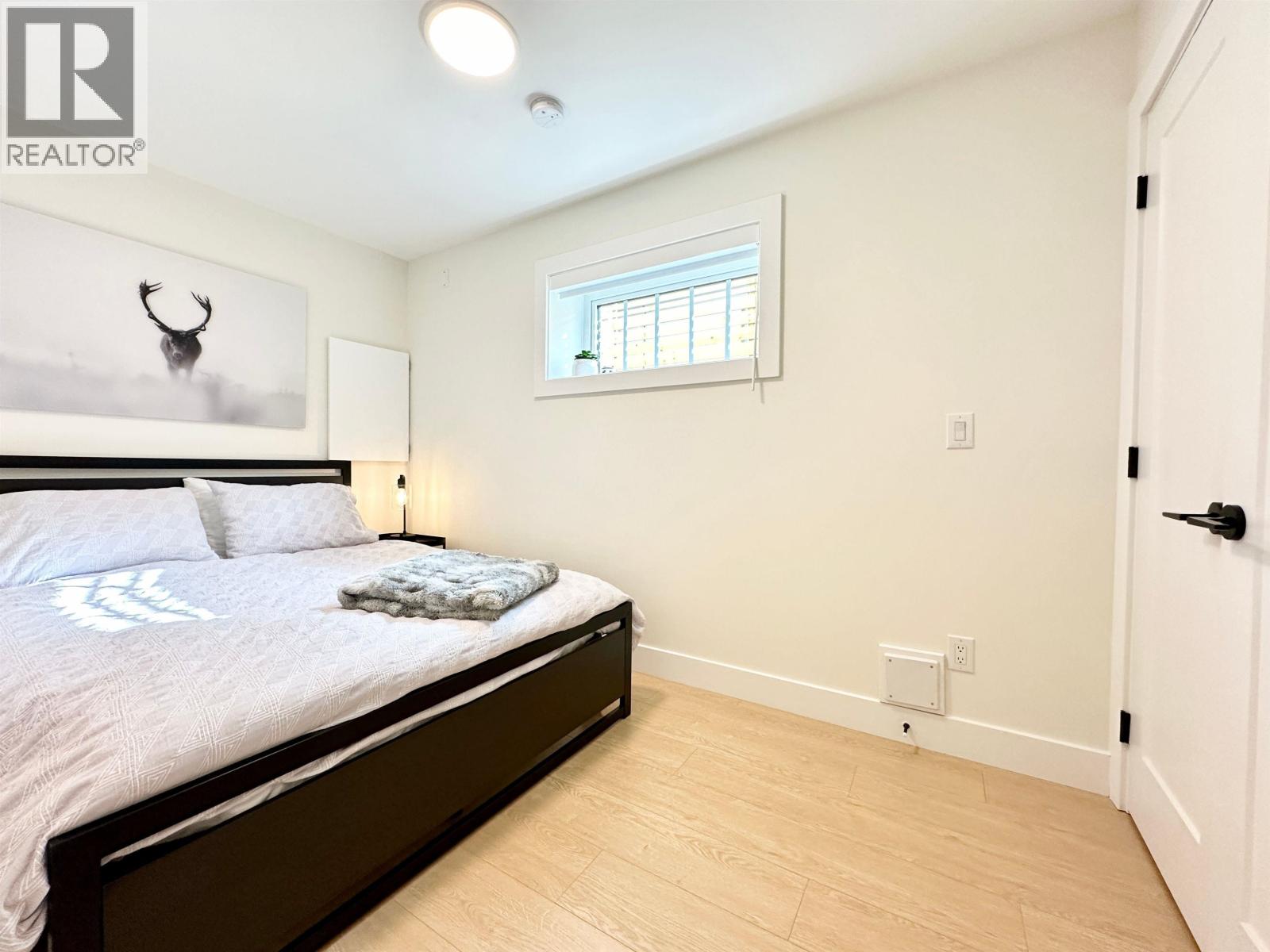 A bedroom with a bed, nightstand, and window.