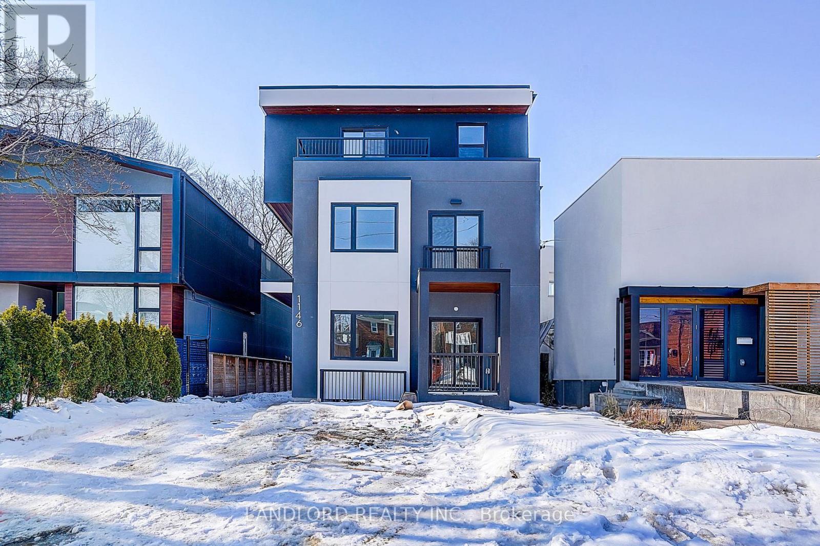 A modern house with a blue and white exterior stands in the snow.