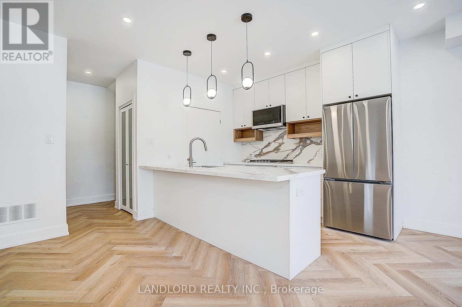 A kitchen with a white counter and a stainless steel refrigerator.