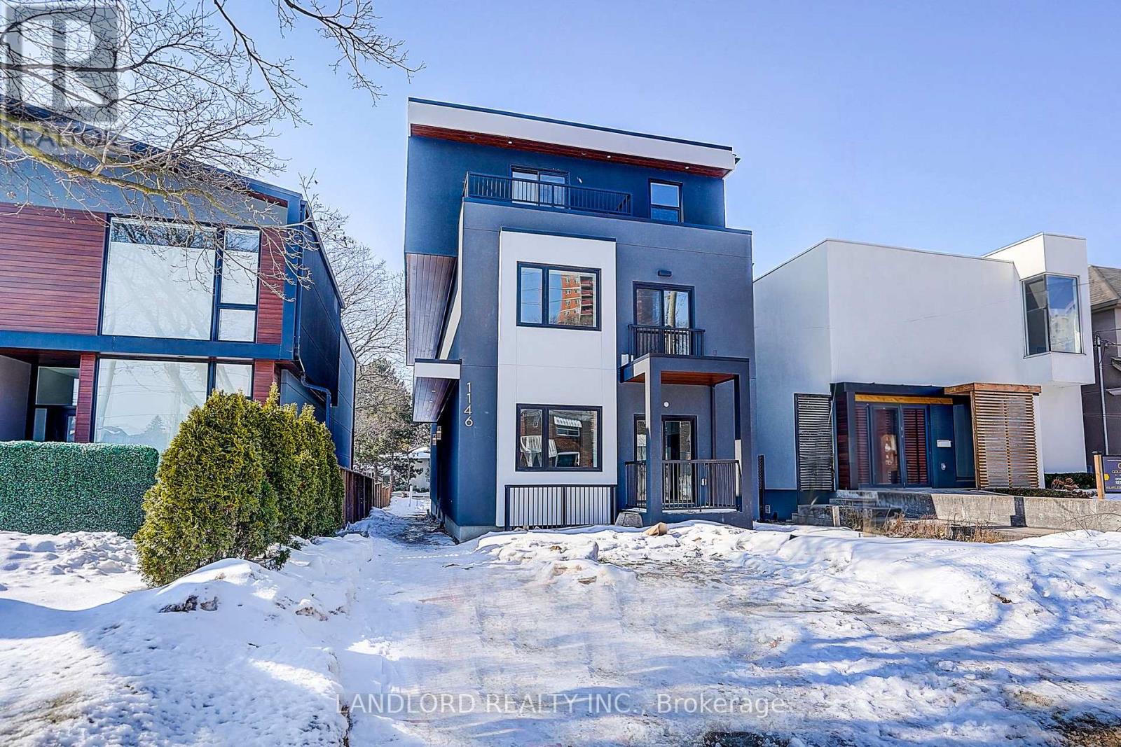 A modern house with a blue and white exterior is surrounded by snow.