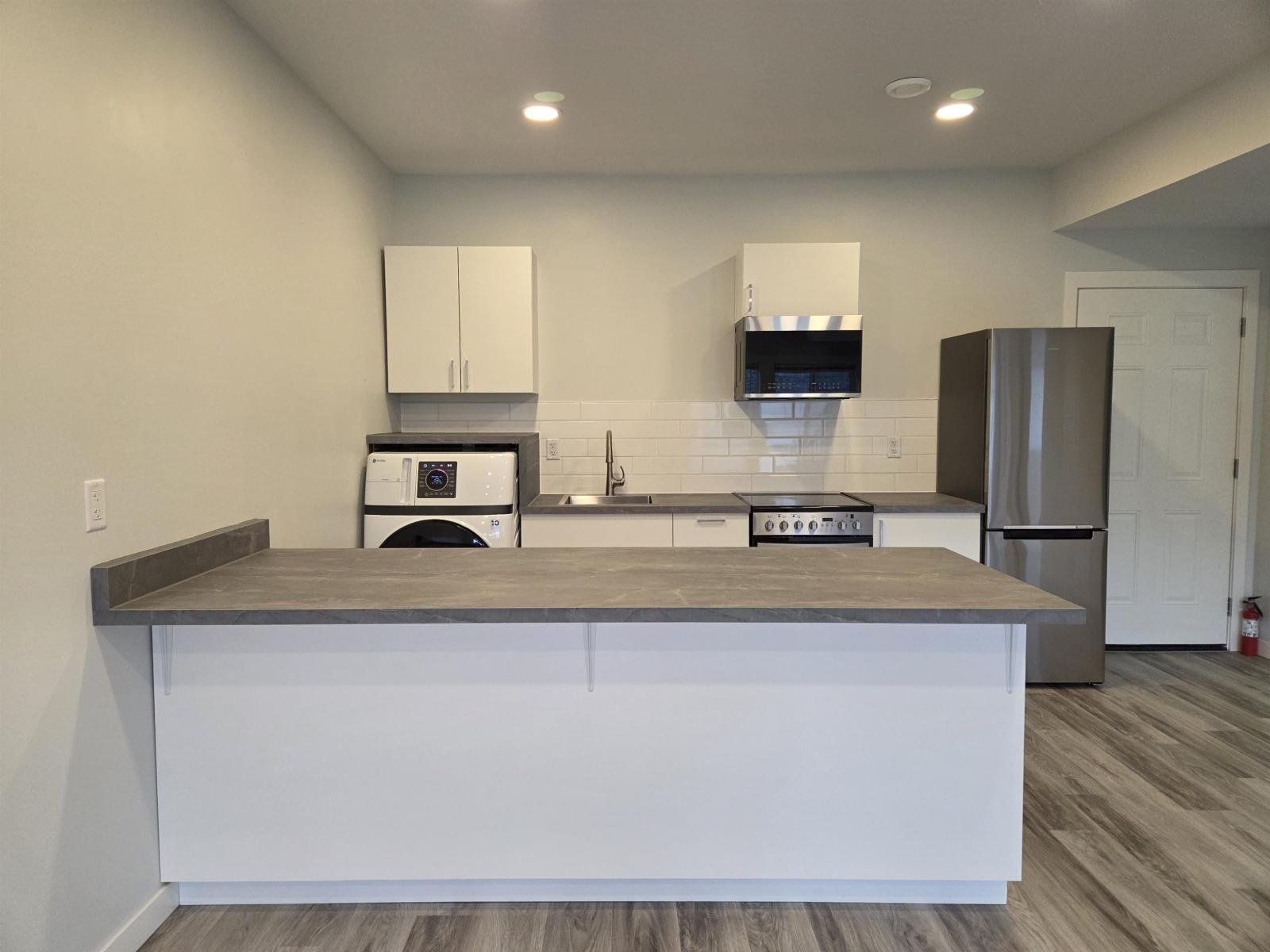 A modern kitchen with white cabinets and a wooden island.