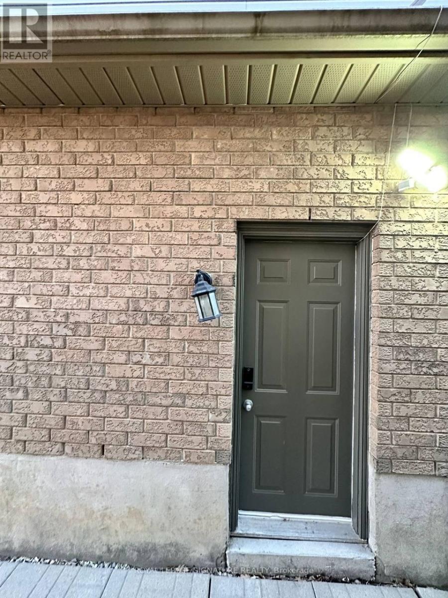 A brown door with a black handle and a black lamp on the wall.