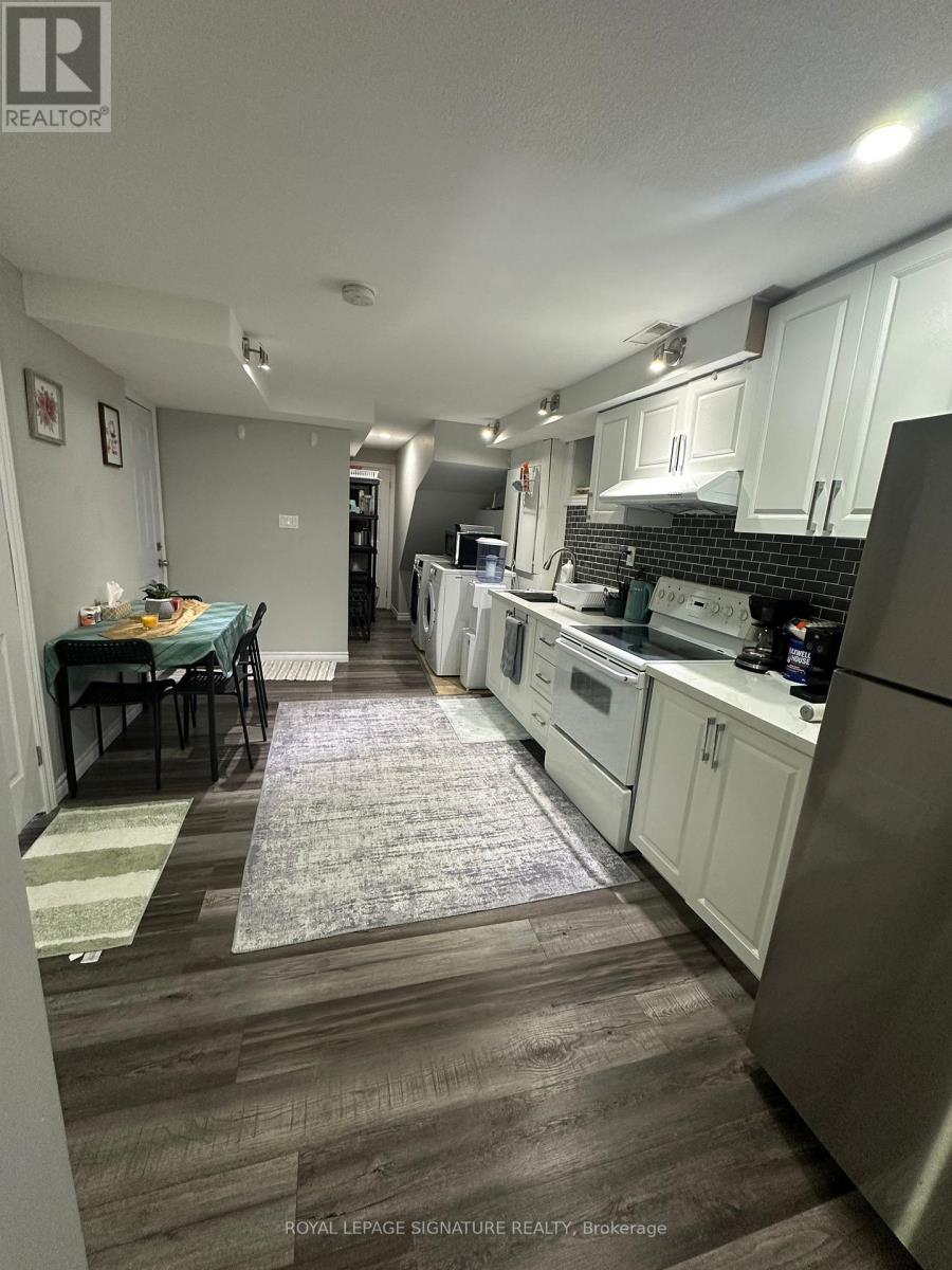 A kitchen with white cabinets and a black tile backsplash.