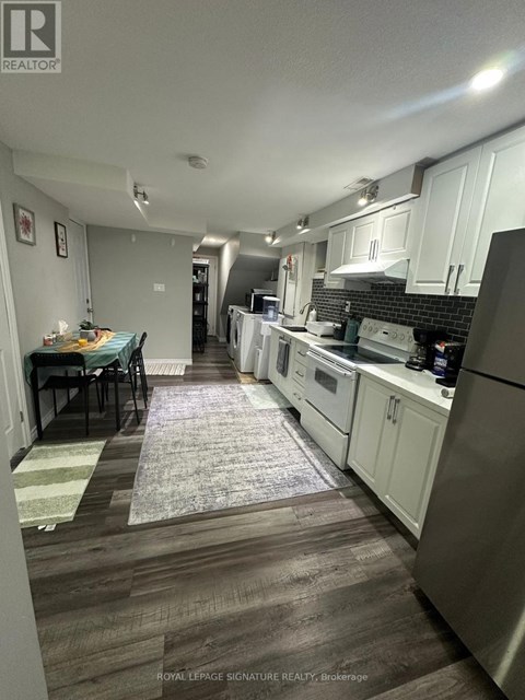 A kitchen with white cabinets and a black tile backsplash.