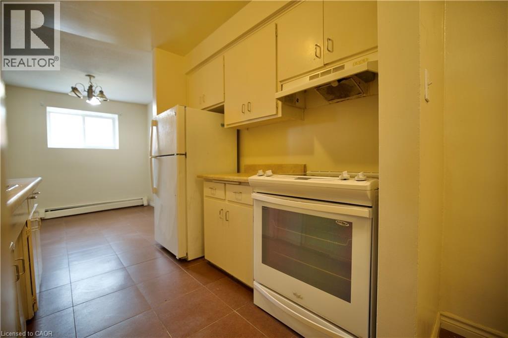 A kitchen with white appliances and brown tile flooring.