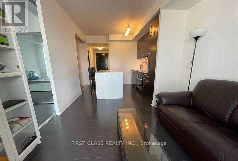 A living room with a brown couch and a glass table.