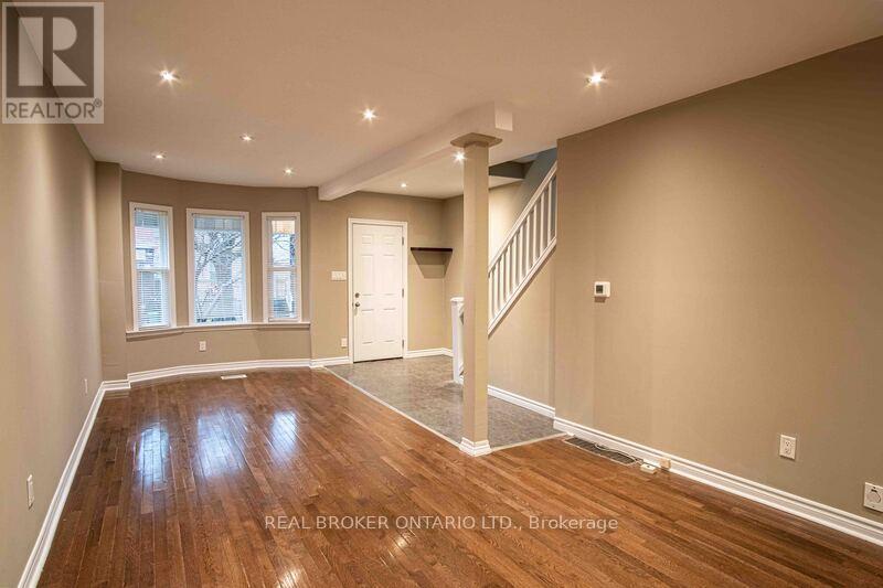 A spacious room with wood flooring and a staircase leading to another level.